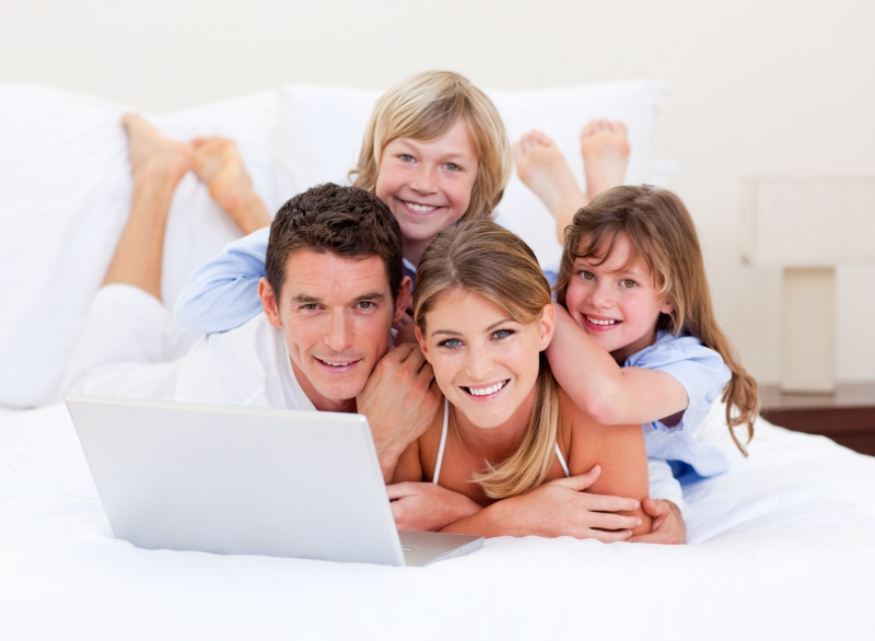 3675189-smiling-family-looking-at-a-laptop-lying-down-on-bed